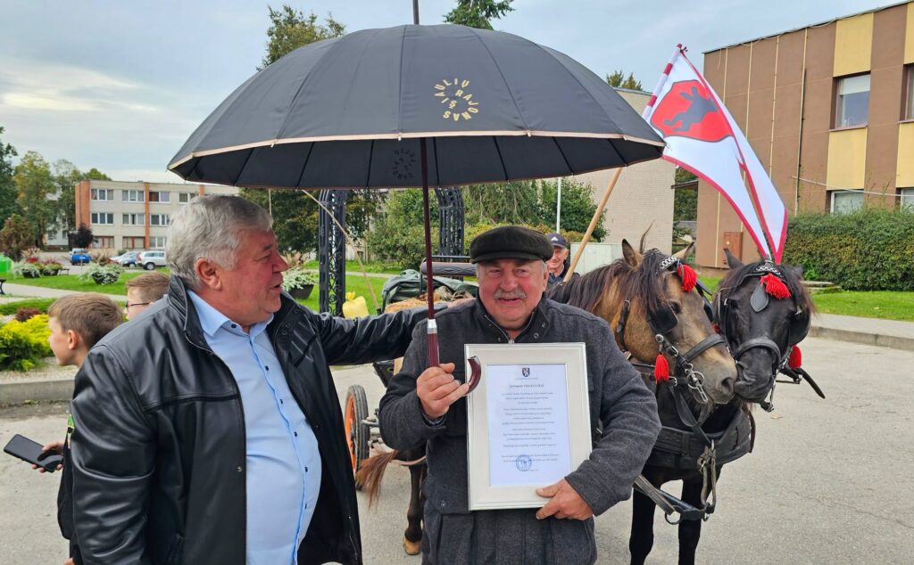 Antanas Bezaras įteikia padėką Vidui Kūlokui Kužiuose, šalia stovi žemaitukų žirgai.