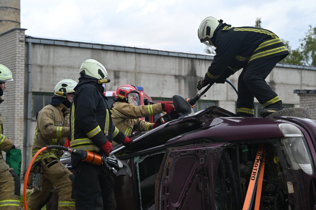 Pakruojo ugniagesiai gelbėtojai pratybų metu dirba prie ant šono apversto automobilio.
