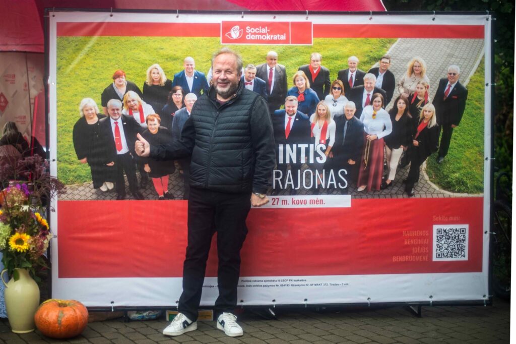 LSDP Šiaulių rajono skyriaus pirmininkas Jonas Kiriliauskas Kuršėnų Jomarke fotografuojasi prie socialdemokratų kandidatų į savivaldybės tarybą stendo.