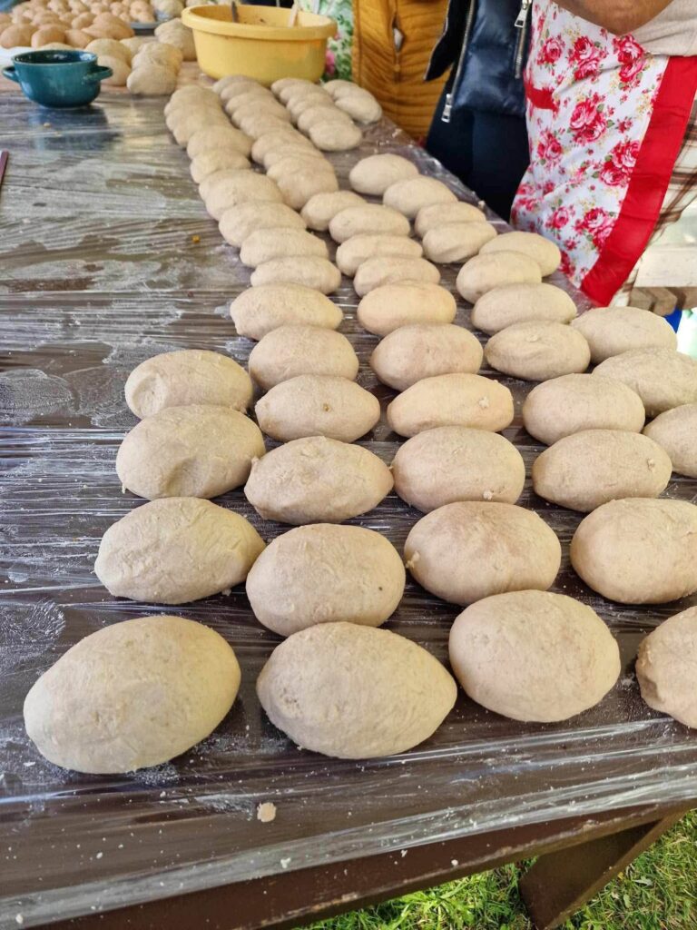 Ant stalo išrikiuoti šviežiai sulipdyti cepelinai per „Cepelinų balių 2026“ Gilvyčiuose, ruošiami virti dideliuose katiluose.