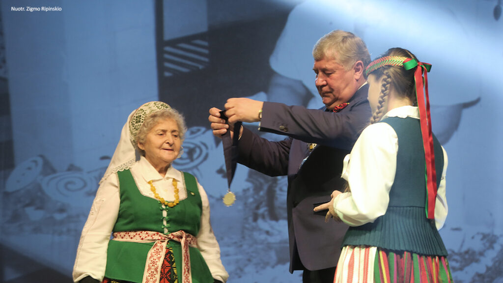 Eugenija Dragūnienė 2020 m. Šiaulių rajono garbės piliečio vardo suteikimo ceremonijoje, meras Antanas Bezaras jai uždeda regalijas.