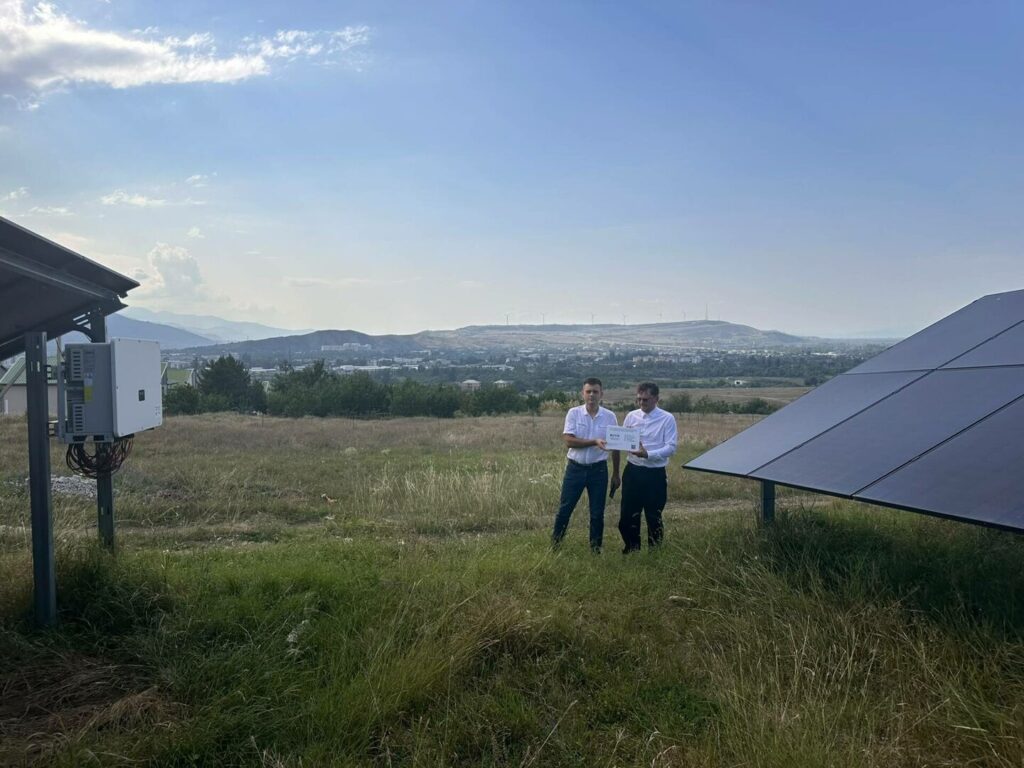 Du vyrai prie saulės elektrinės modulių Goryje, Sakartvele, kur įgyvendintas 718 kW galios saulės energetikos projektas dėl karo perkeltoms šeimoms.
