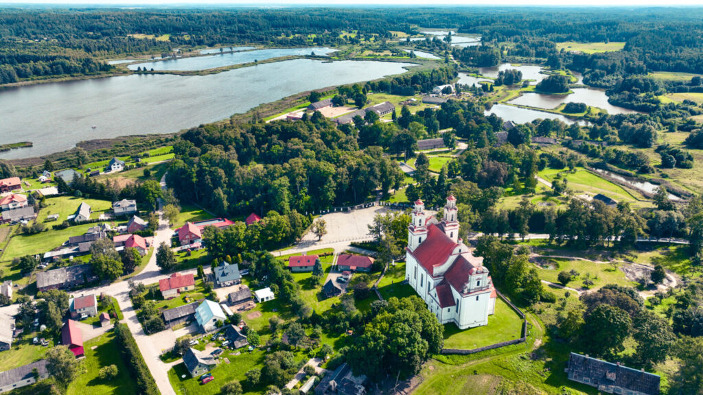 Kurtuvėnų miestelio panorama iš paukščio skrydžio – Šv. apaštalo Jokūbo bažnyčia, miestelio aikštė ir miškų apsupti Kurtuvėnų žuvininkystės tvenkiniai.