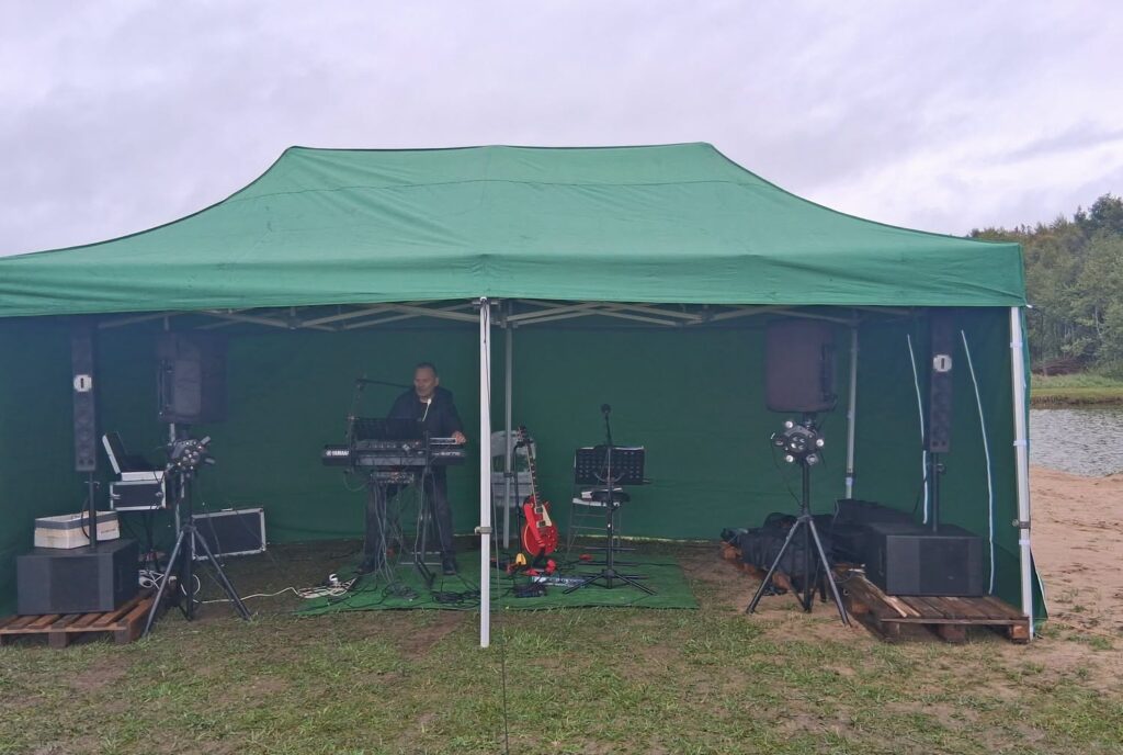 Žalioje renginių palapinėje prie Noreikių bendruomenės tvenkinio įrengta scena su muzikos aparatūra ir instrumentais.
