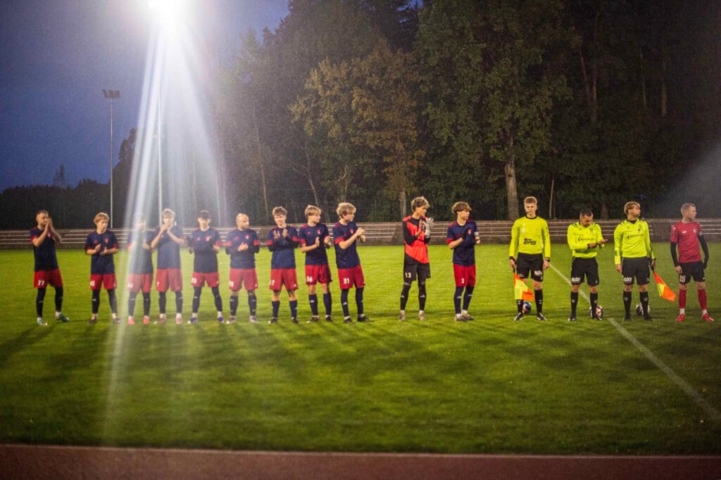 Kuršėnų futbolo klubo „Venta“ žaidėjai po rungtynių stadione ploja žiūrovams. Šalia futbolininkų stovi rungtynių teisėjai.